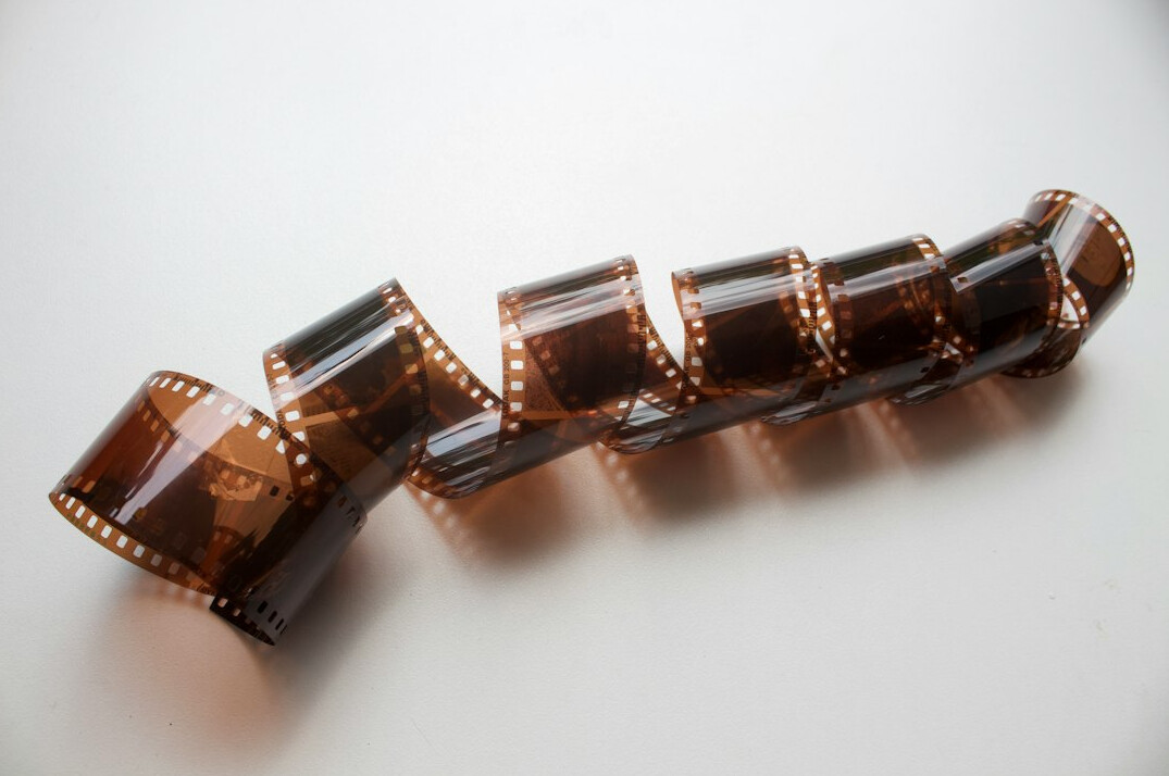 Hands carefully cleaning an old film reel on a worktable