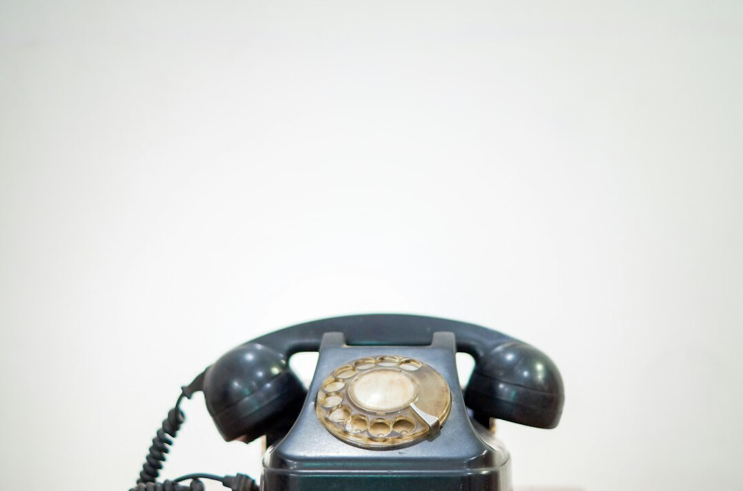 Vintage rotary telephone and notepad on a wooden desk
